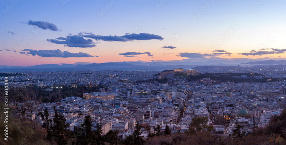 View of the city of Athens, during sunset. On the right there can be seen Acropolis and the Parthenon, and on bottom left the Greek Parliament.