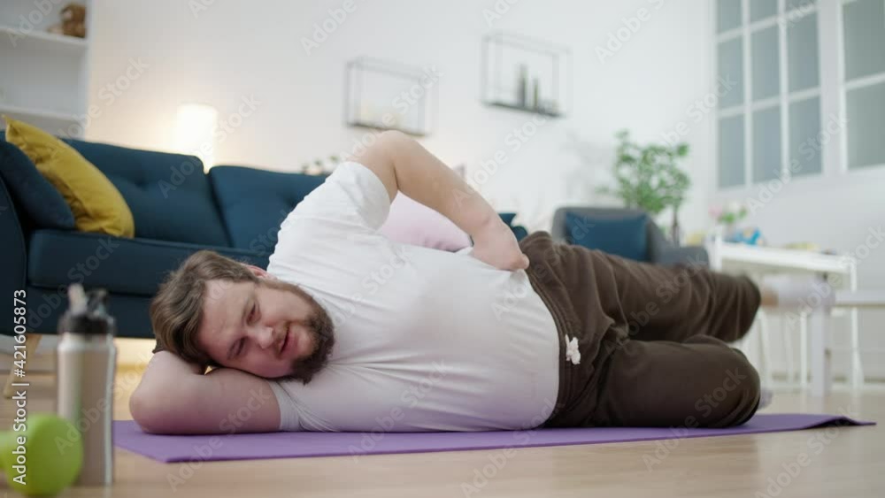 Chubby man doing exercise on mat, making effort to lose weight, motivation Chubby man doing exercise on mat, making effort to lose weight, motivation