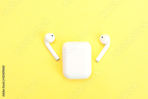 White wireless headphones on a yellow background. 