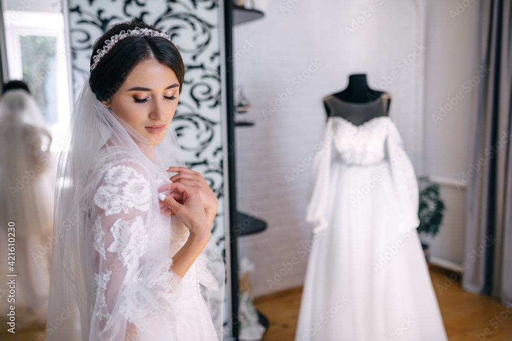 Morning of the bride. A beautiful girl stands in a white robe. Dress with lace on a mannequin Morning of the bride. A beautiful girl stands in a white robe. Dress with lace on a mannequin