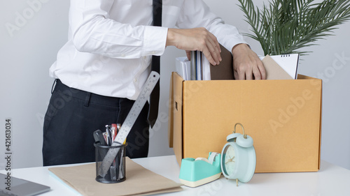 Put the work equipment in the office in a large brown box, Businessmen are keeping work documents and personal belongings due to resignation or being fired, termination of employment.