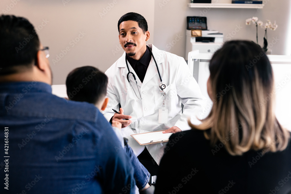 Hispanic family doctor consulting with patients in doctors office Hispanic family doctor consulting with patients in doctors office