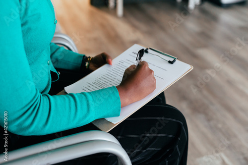 Black woman completing medical paperwork and healthcare forms on clipboard