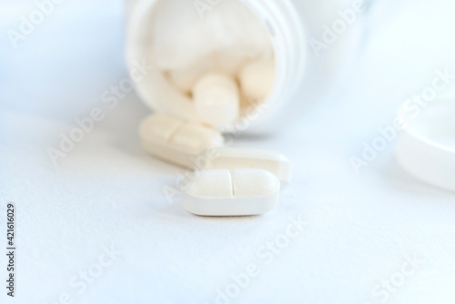White pills and bottle on a white background, close up, isolated