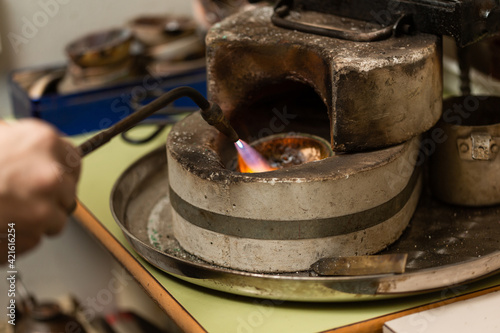 blowtorch melts silver in a jewelry workshop furnace