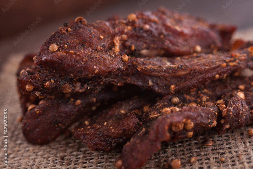 Organic Dried Pork with Pepper Dried Seal, Studio Shot. Jerky on sacking. Wooden background. 