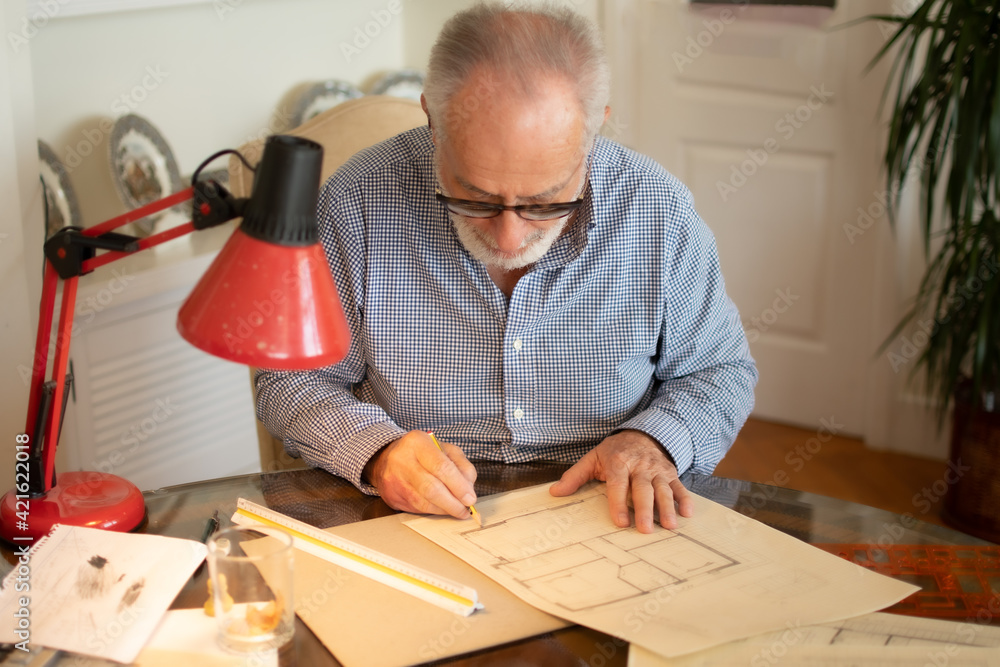 Older man entertaining drawing some plans at home Older man entertaining drawing some plans at home