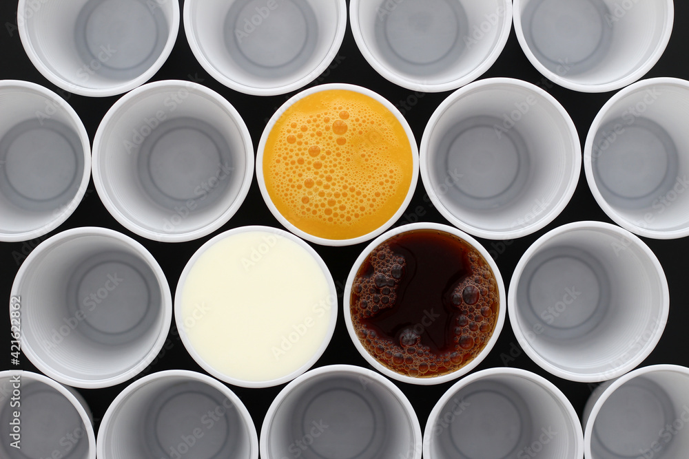 Orange juice, tea and milk together in white plastic disposable cups, view from above Orange juice, tea and milk together in white plastic disposable cups, view from above
