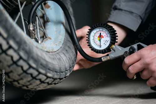 Quadro su tela A worker is inflating a motorbike wheel by the car tyre inflating gun close up