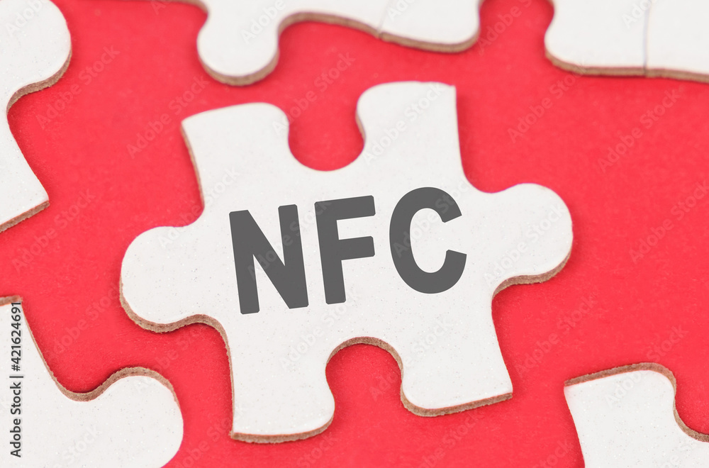 On a red background, among white puzzles lies a puzzle with the inscription - NFC On a red background, among white puzzles lies a puzzle with the inscription - NFC