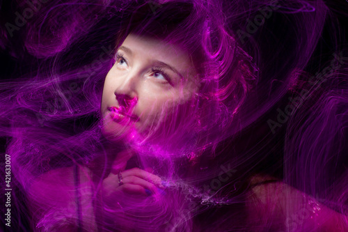 beautiful girl model with cosmic make-up on face, blue and purple color on dark background , longexposure foto