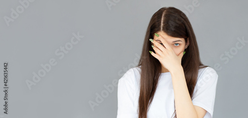 Young woman with hand on her face isolated on gray background, facepalm photo