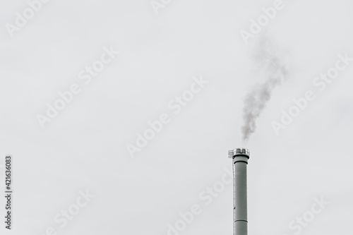 Grey smoke coming out of an industrial chimney in front of a grey sky