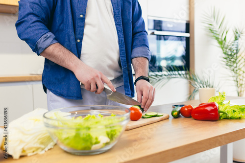 Close-up photo, a man at home chops vegetables in the kitchen, prepares breakfast