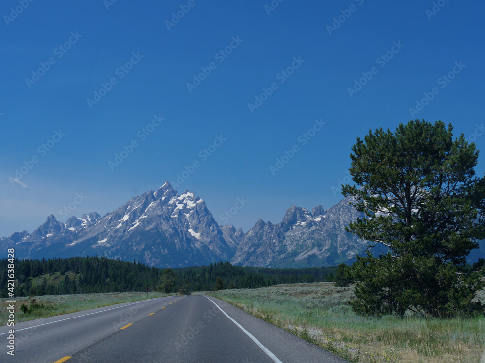 Scenic drive with the Grand Teton Mountain ranges in the distance, Wyoming.