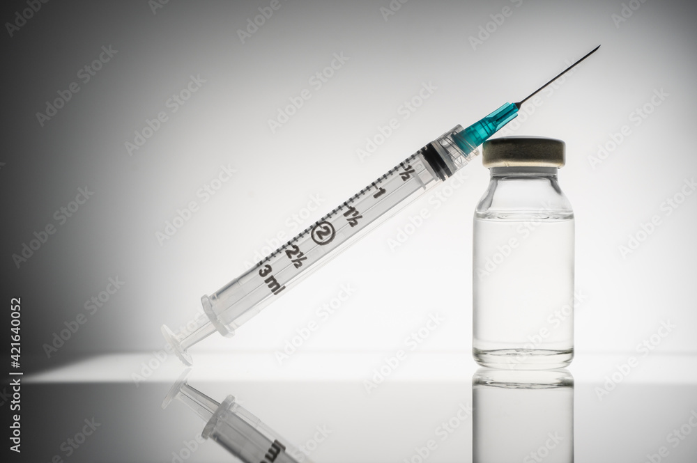 Studio shot of laboratory vial with liquid and syringe Studio shot of laboratory vial with liquid and syringe