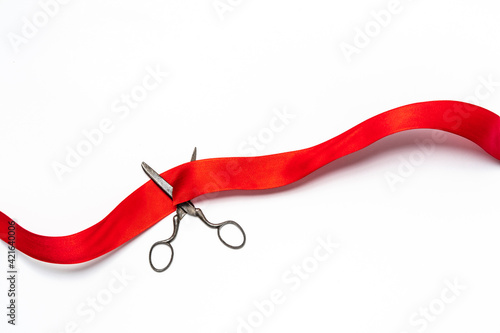 Studio shot of old fashioned scissors cutting red ribbon photo