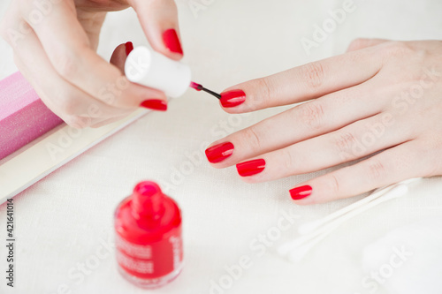 Woman painting her nails with red nail polish