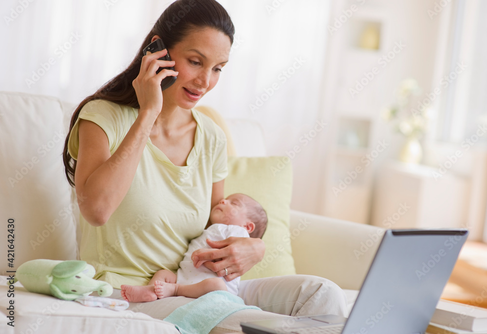 Mother talking on phone while holding her baby Mother talking on phone while holding her baby