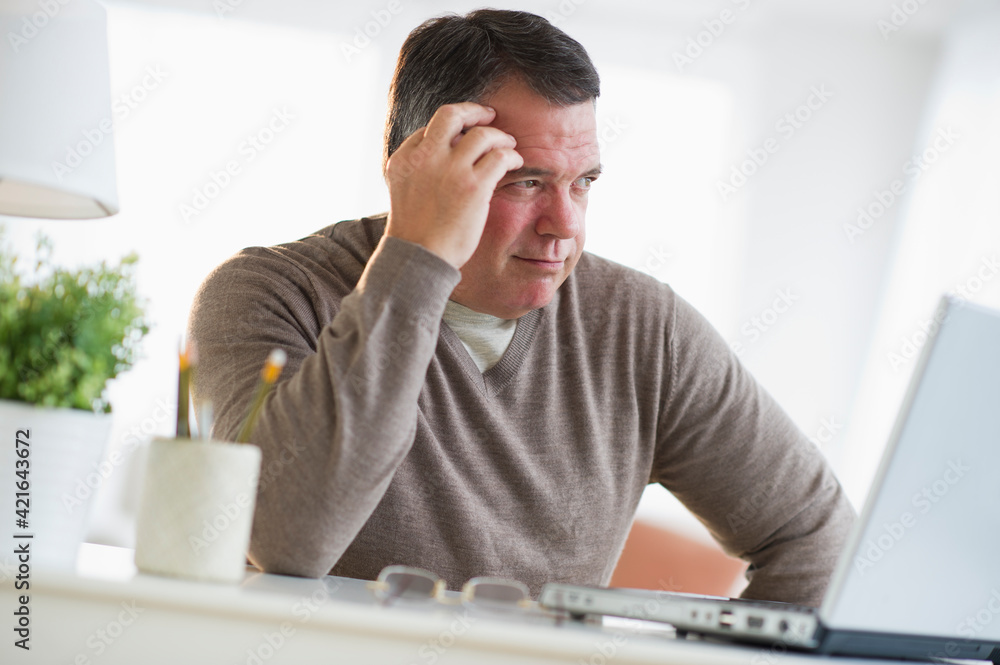 USA, New Jersey, Jersey City, Pensive man using laptop in living room USA, New Jersey, Jersey City, Pensive man using laptop in living room