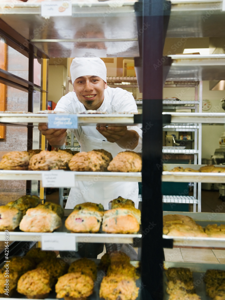 Baker standing behind trays of baked goods Baker standing behind trays of baked goods