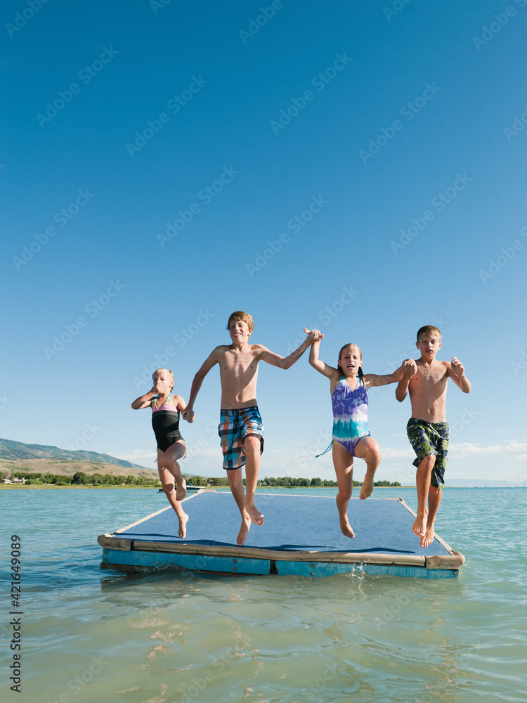 Kids (6-7,8-9,10-11,12-13) playing on raft on lake Kids (6-7,8-9,10-11,12-13) playing on raft on lake