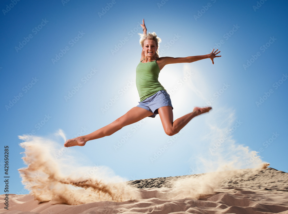 Female dancer jumping in sand Female dancer jumping in sand