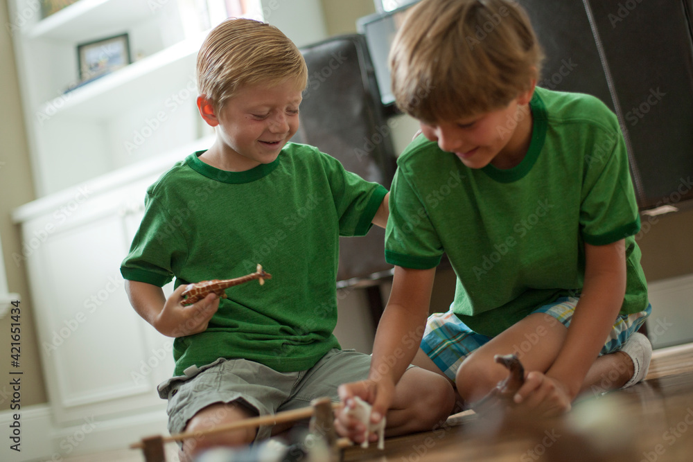 Two boys playing with toy animals Two boys playing with toy animals