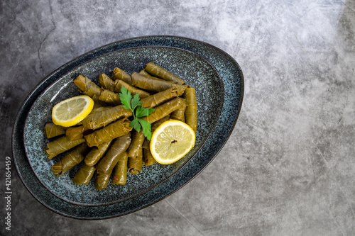 Top view, Plate with delicious, stuffed grape leaves with parsley and lemons called Dolma , made from vines with rice, meat and spices.