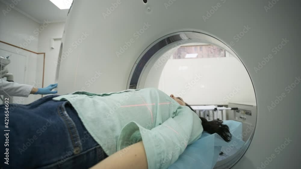 Female patient is undergoing CT or MRI scan under supervision of ...