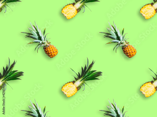 Seamless pattern of ripe pineapples isolated on green background. Top view. Exotic tropical fruit summer concept