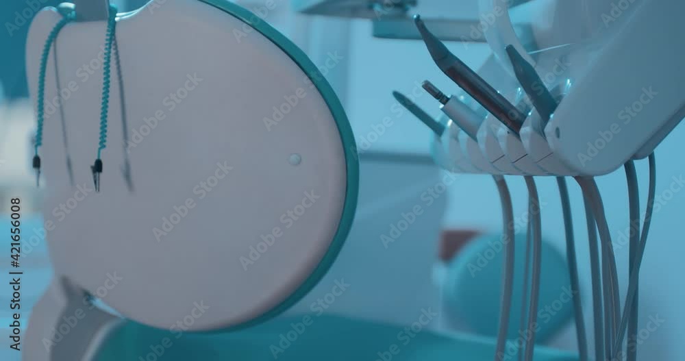 Close-up back of a dental chair and holder with a dental equipment and is standing at the dentist office next to the dentist chair. Close-up back of a dental chair and holder with a dental equipment and is standing at the dentist office next to the dentist chair.