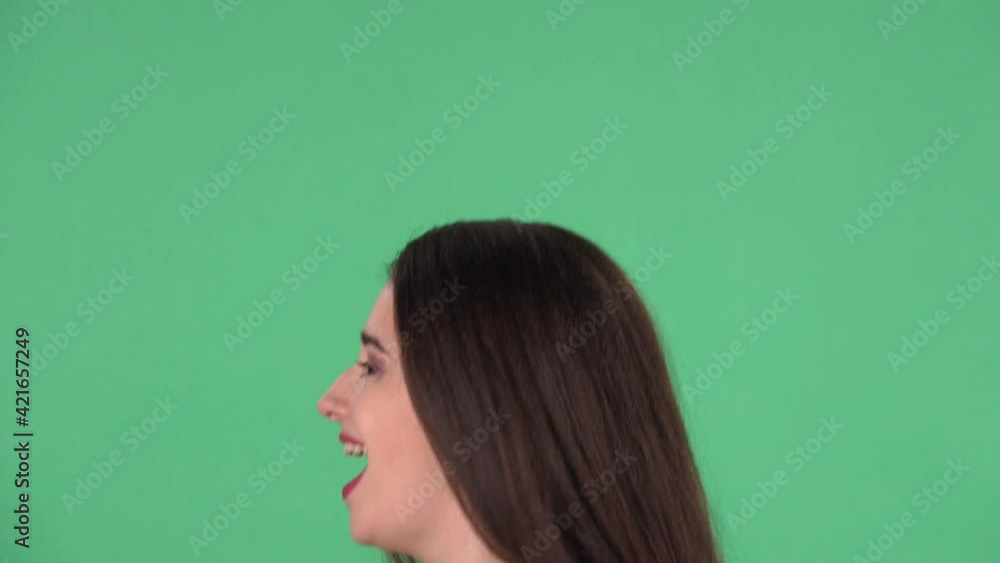 Portrait of beautiful young woman sings song into microphone and dances to music. Model with long hair in red dress posing on green screen in the studio. Side view. Slow motion. Close up. Portrait of beautiful young woman sings song into microphone and dances to music. Model with long hair in red dress posing on green screen in the studio. Side view. Slow motion. Close up.