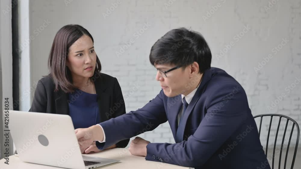 Angry furious and serious concept. Asian male manager in suit wearing glasses angry and blame to female secretary with laptop in coffee shop. Businessman and businesswoman argue dispute about project. Angry furious and serious concept. Asian male manager in suit wearing glasses angry and blame to female secretary with laptop in coffee shop. Businessman and businesswoman argue dispute about project.