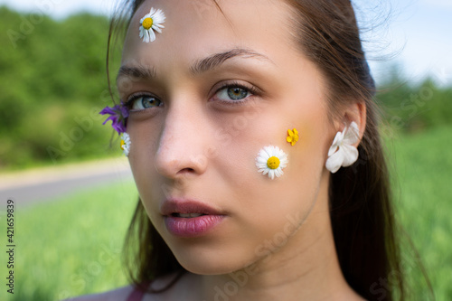 Beauty model girl with wild flowers and daisy glued to her skin. cosmetic masks, patches, herbal decoctions for skin health, herbal detox concept. beautiful woman with wild flowers and daisy on face