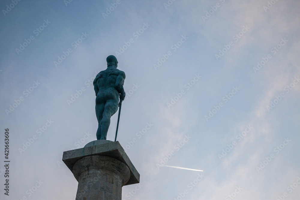 Fototapeta premium Close up on the Victor statue on Kalemegdan fortress, during a sunny sunset afternoon, seen from behind. Also called Viktor Pobednik, Located in Kalemegdan fortress, it's a landmark of the city