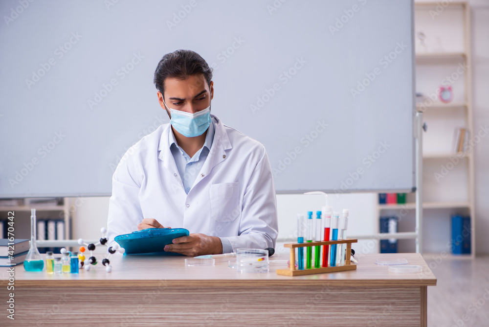 Young male chemist teacher sitting in the classroom Young male chemist teacher sitting in the classroom