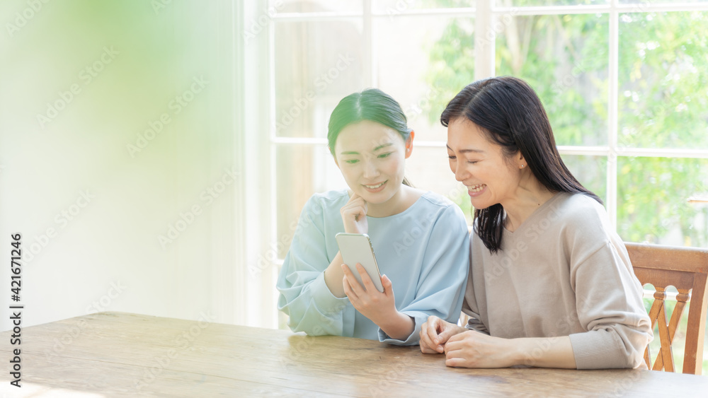 リビングでスマートフォンを使う親子 リビングでスマートフォンを使う親子