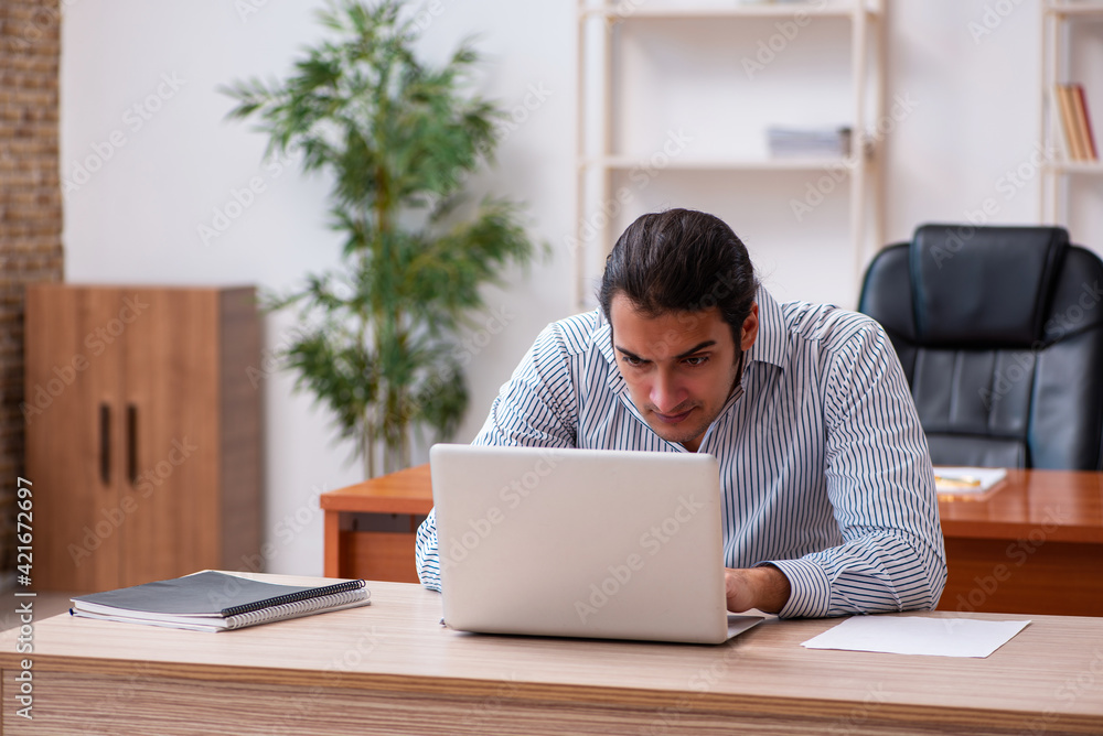 Young male employee sitting in the office Young male employee sitting in the office