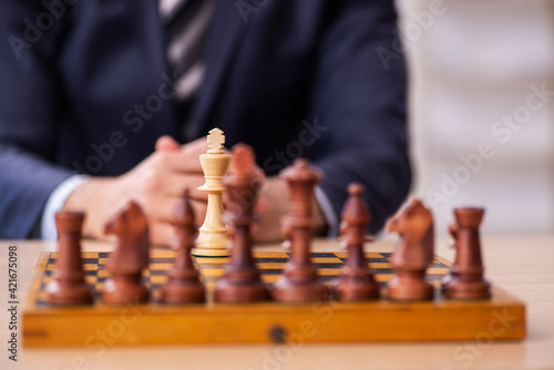 Young male employee playing chess at workplace