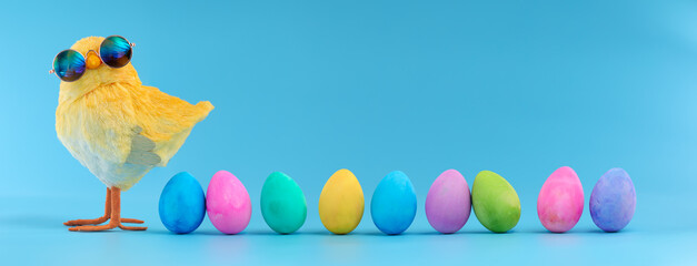 Easter decoration of a yellow chick wearing silly sunglasses with a row of colorful painted Easter eggs.