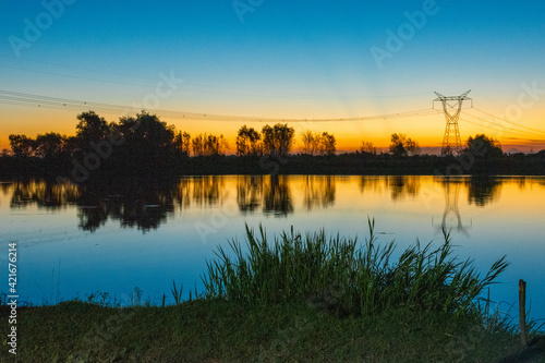 beautiful postcard of a sunset in a river in Argentina with an electric tower