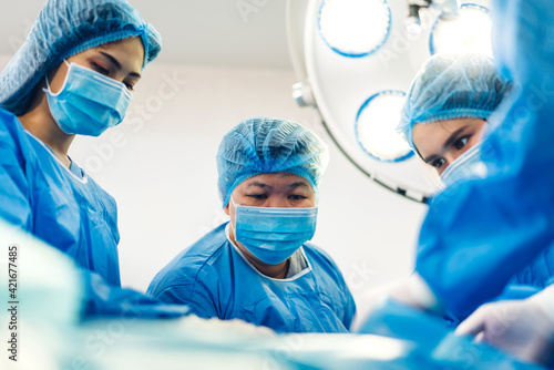 Professional anesthesiologist doctor medical team and assistant preparing patient to gynecological surgery performing operating with surgery equipment in modern hospital operation emergency room