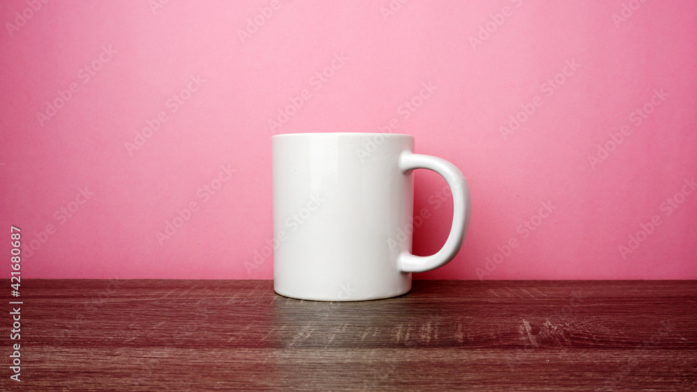 Empty white cup on top of the wooden table on pink background.
Empty white cup on top of the wooden table on pink background.