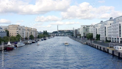 Stockholm, Sweden. Aerial Drone summer view of a beautiful canal and bay at Hammarby Sjöstad with modern architecture, sightseeing boat, and docks with old  houseboats.