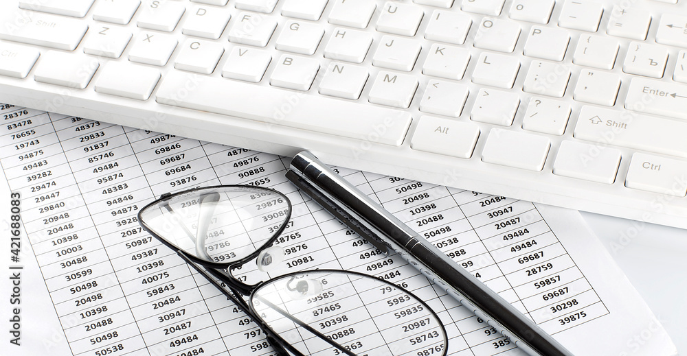 business work with chart,glasses, pen and keyboard on white office desk top view business work with chart,glasses, pen and keyboard on white office desk top view