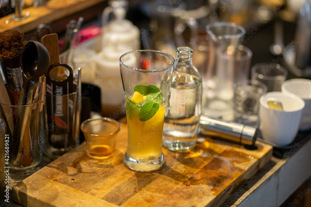 A close-up of a lemon-soda cold drink in a clear glass on the cafe table where the barista is mixing something into the glass. Summer refreshing drink A close-up of a lemon-soda cold drink in a clear glass on the cafe table where the barista is mixing something into the glass. Summer refreshing drink