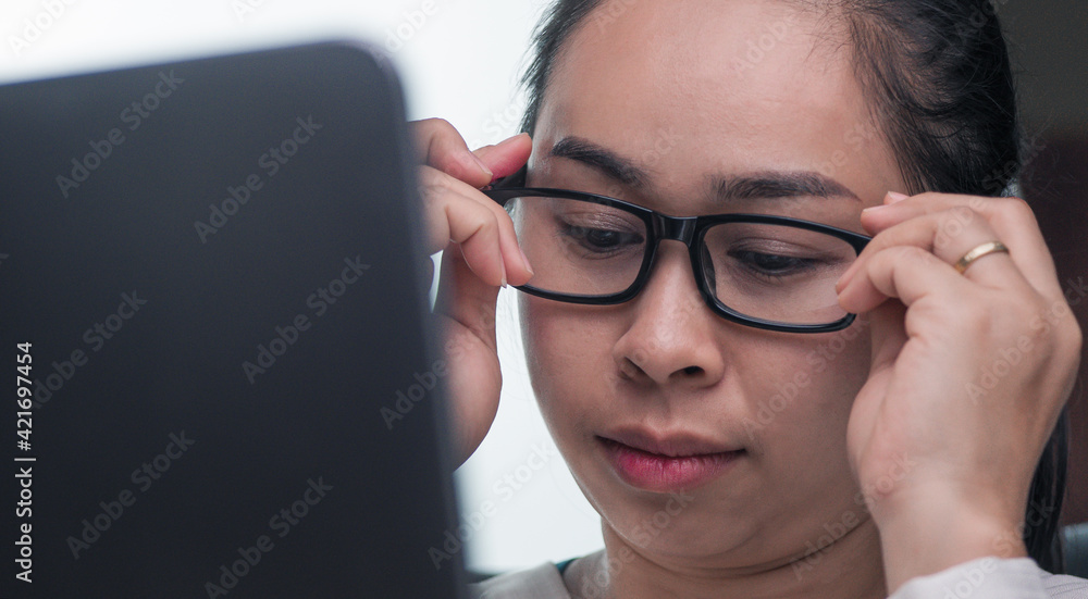 A happy businesswoman in glasses is working on a laptop computer in her office. A happy businesswoman in glasses is working on a laptop computer in her office.