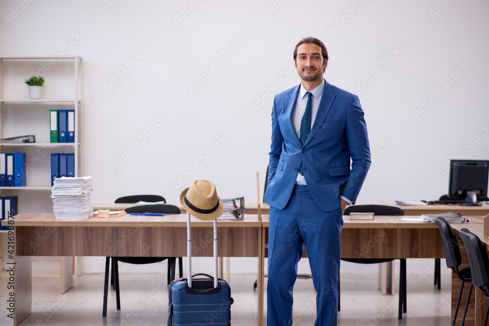 Young male employee preparing for trip in the office Young male employee preparing for trip in the office