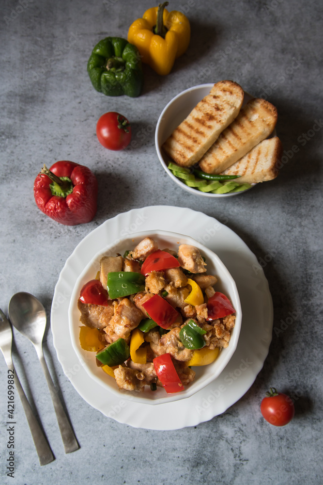 Top view of Chicken pieces and bell peppers in a bowl along with bread with use of selective focus.